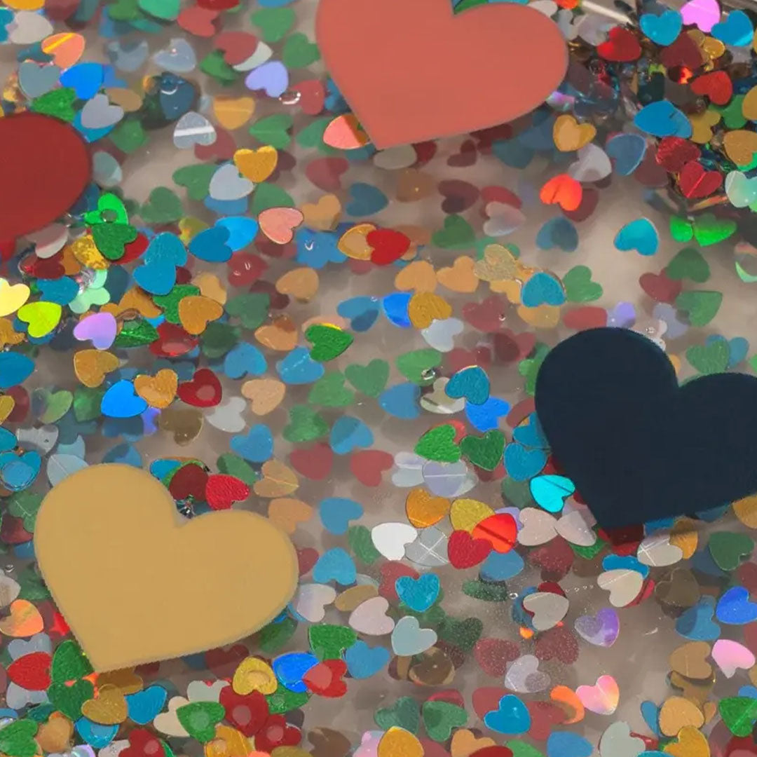Detail van de deksel van een kinderbroodtrommel met kleurrijke glitter en harten.