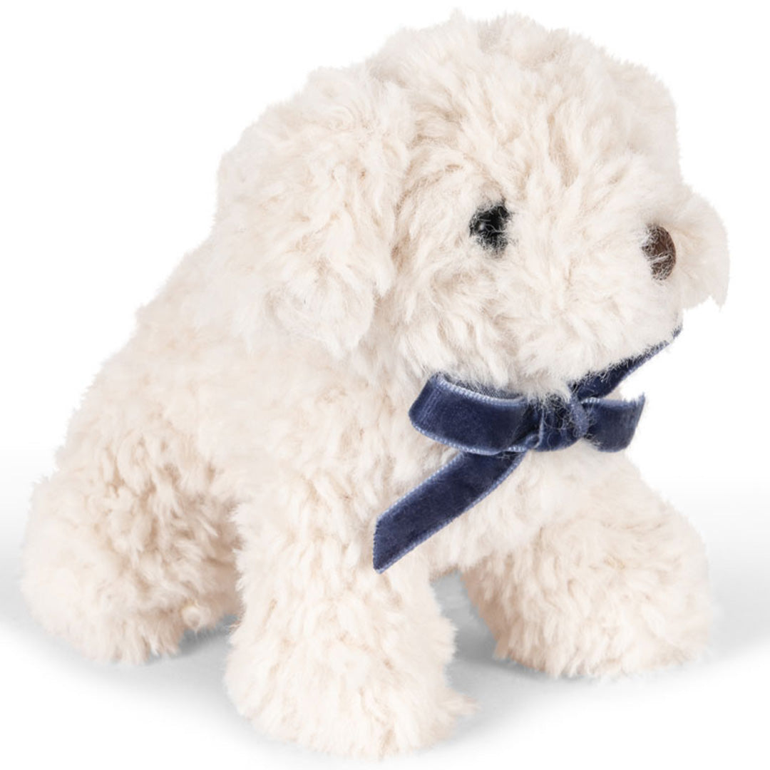 Konges Sløjd witte pluchen knuffelhond met blauwe strik, schuin van voren gefotografeerd.