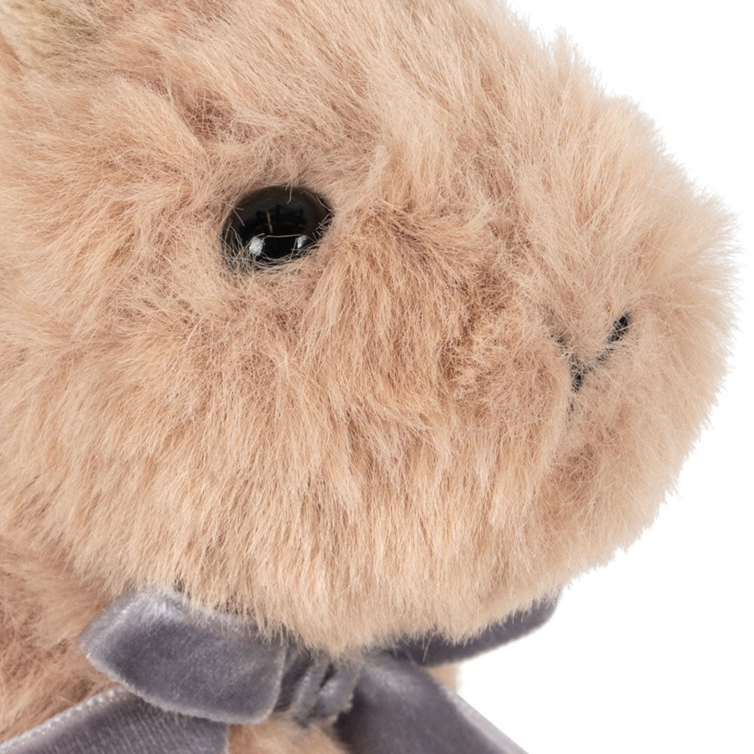 Detailopname van het gezicht van het Konges Sløjd pluchen knuffelkonijn met zwart oog en grijs strikje.
