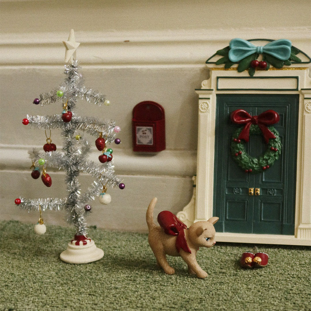 De konges sløjd kerstdecoratie set met kerstboom, deur, katje en rode brievenbus op een groene vloer.
