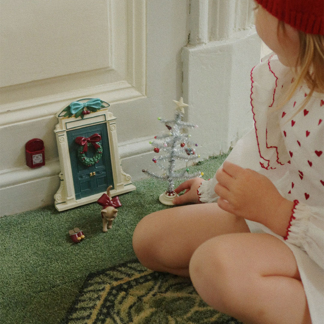 Een kind speelt met de konges sløjd kerstdecoratie set op een groene vloer.