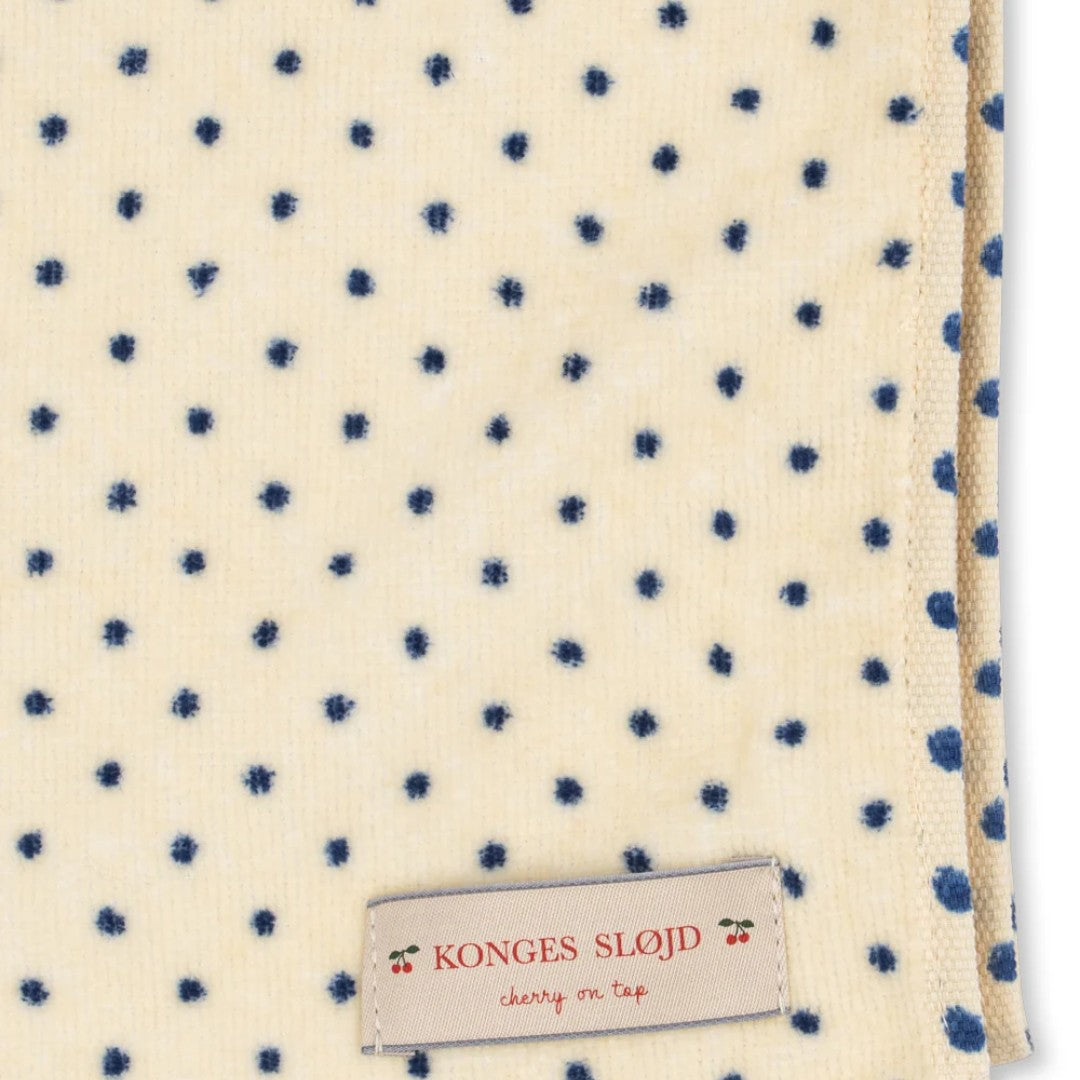 Detail van het Konges Sløjd strandlaken met blauwe stippen en het merklabel.