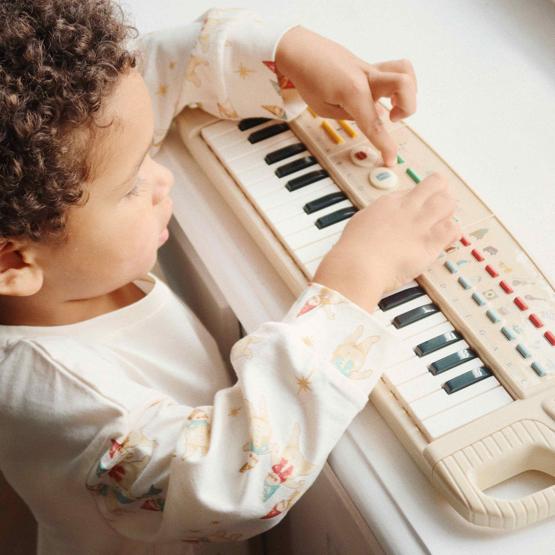 Een kind speelt met het Konges Sløjd beige speelgoedkeyboard.