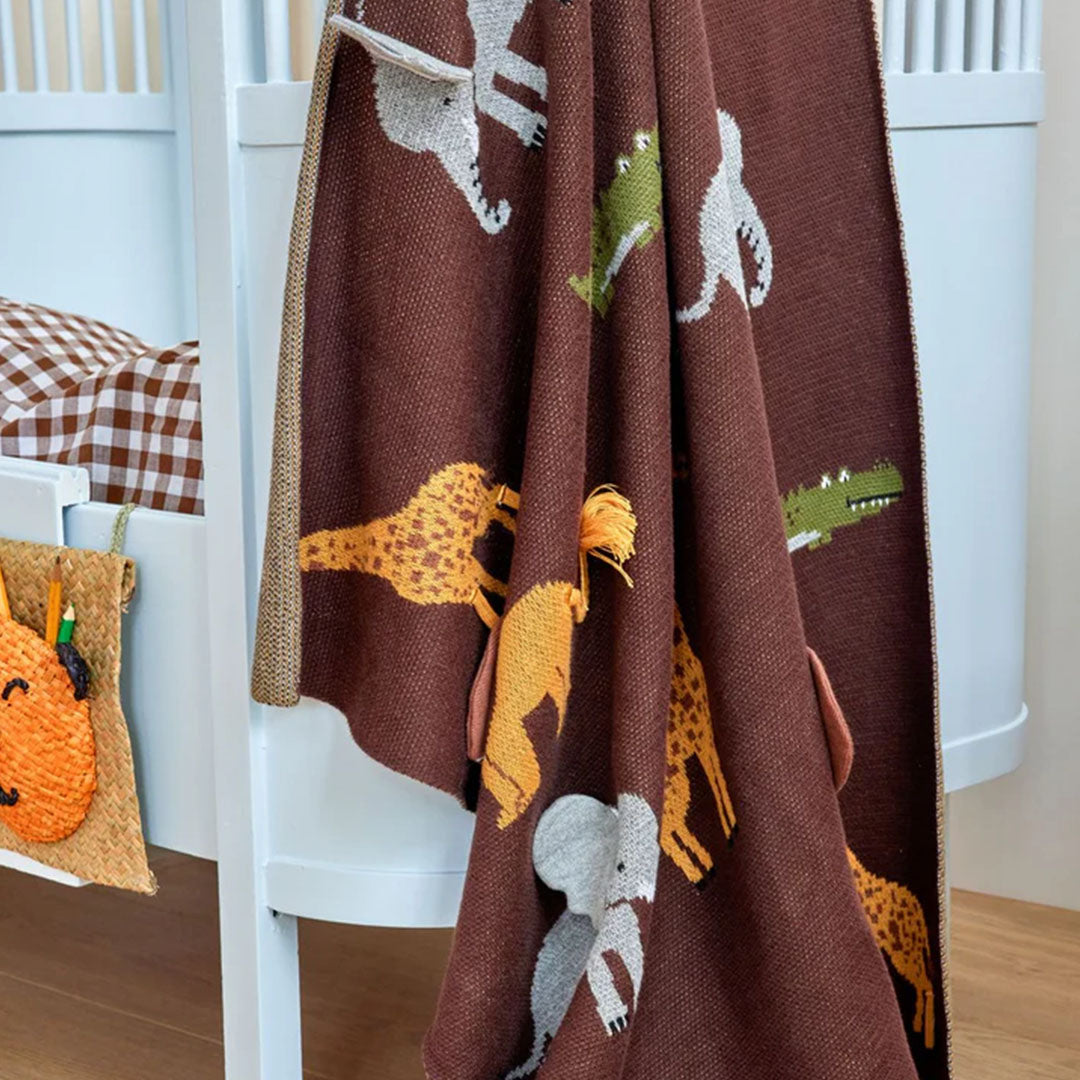 Rice babydeken met savanne dieren hangend over een wit babybedje.