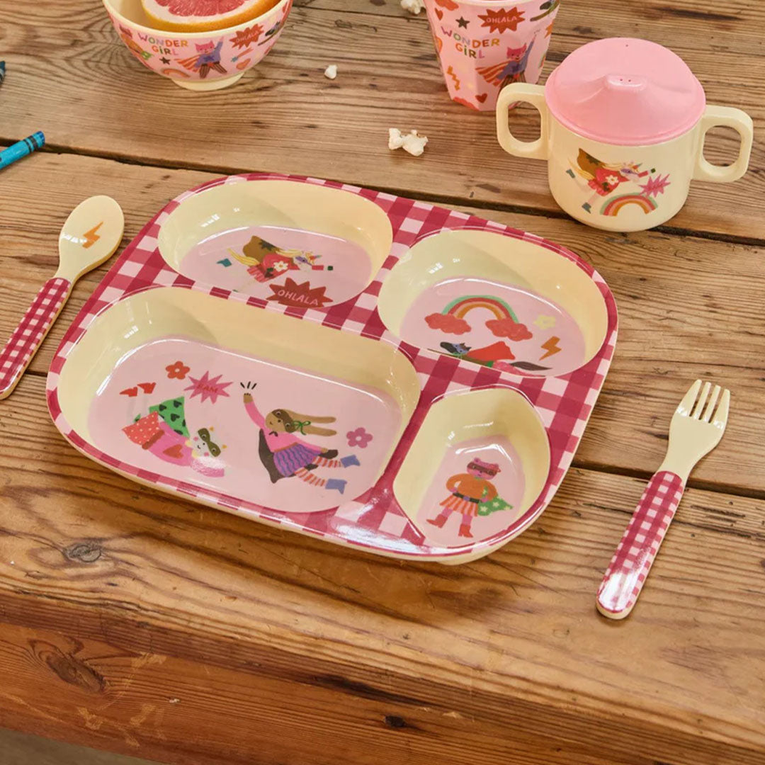 Rice kinderservies met roze hero-thema op een houten tafel, bestaande uit een verdeeld bord, beker, lepel en vork.