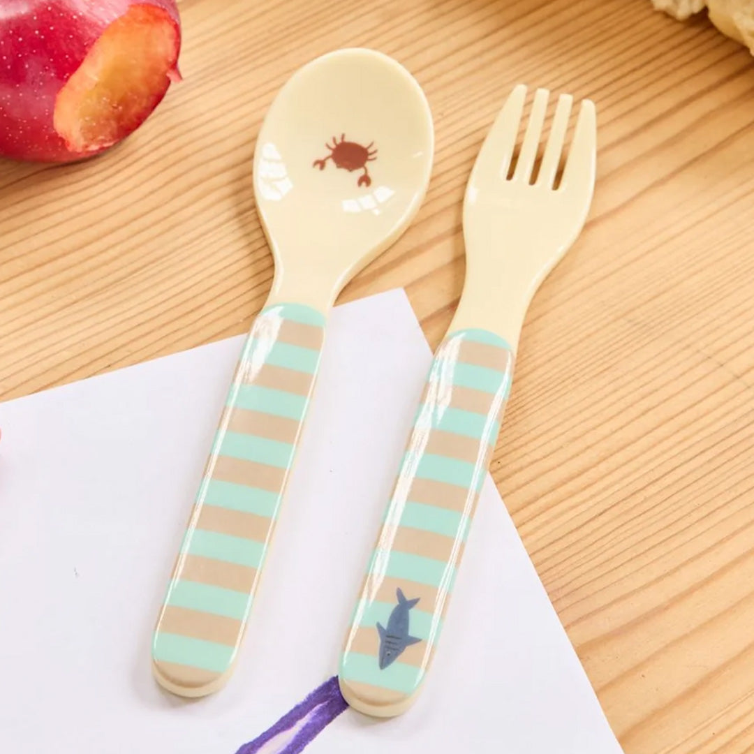 rice kinderbestek met gestreepte handvatten en zeedieren, liggend op een houten ondergrond.