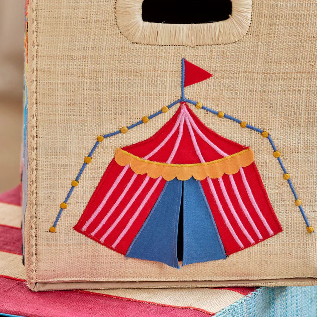 Detail van de raffia opbergmand met een geborduurde rode en blauwe circustent.