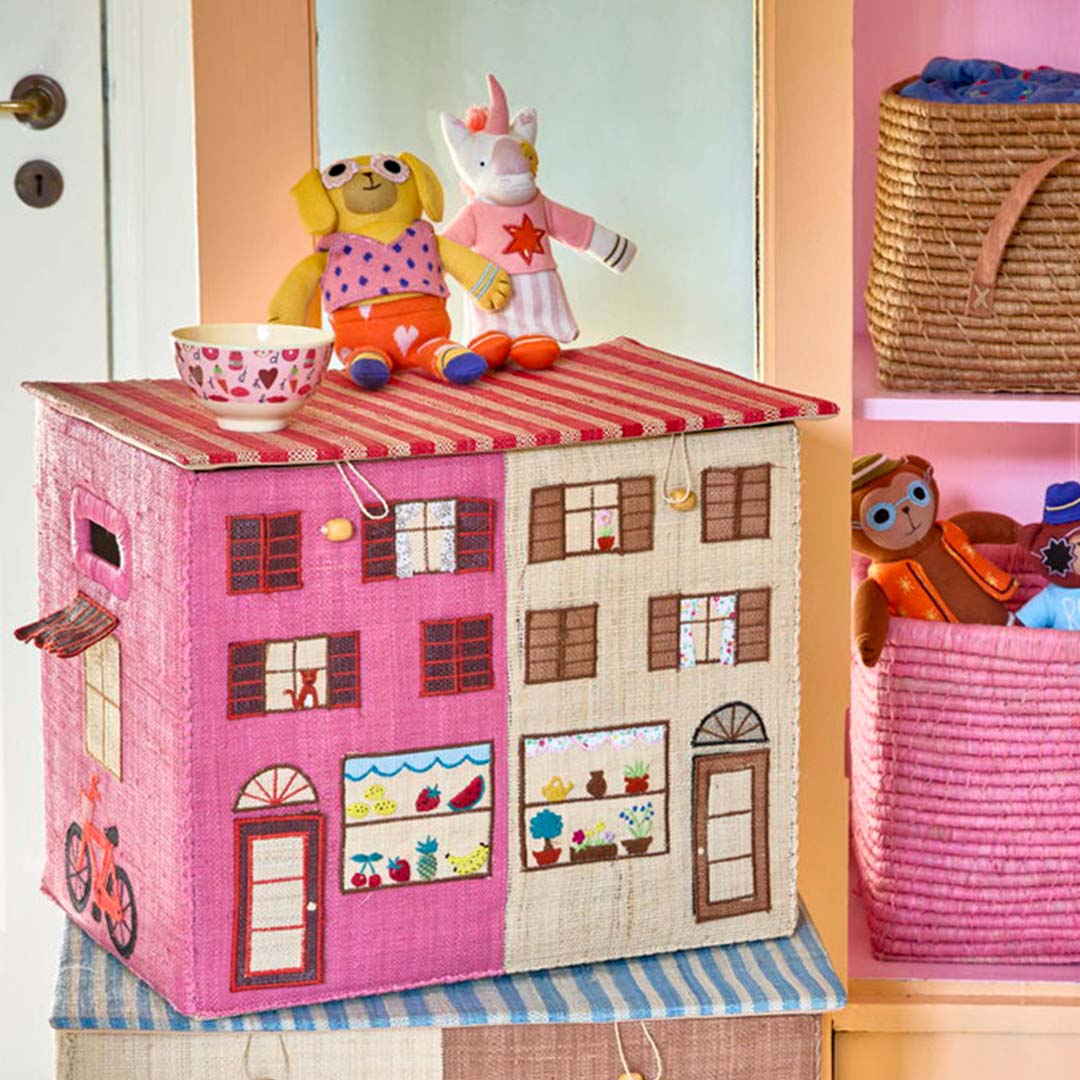 Rice opbergmand met Parijs thema in de vorm van een huis, met knuffels en een kom erop in een kinderkamer.