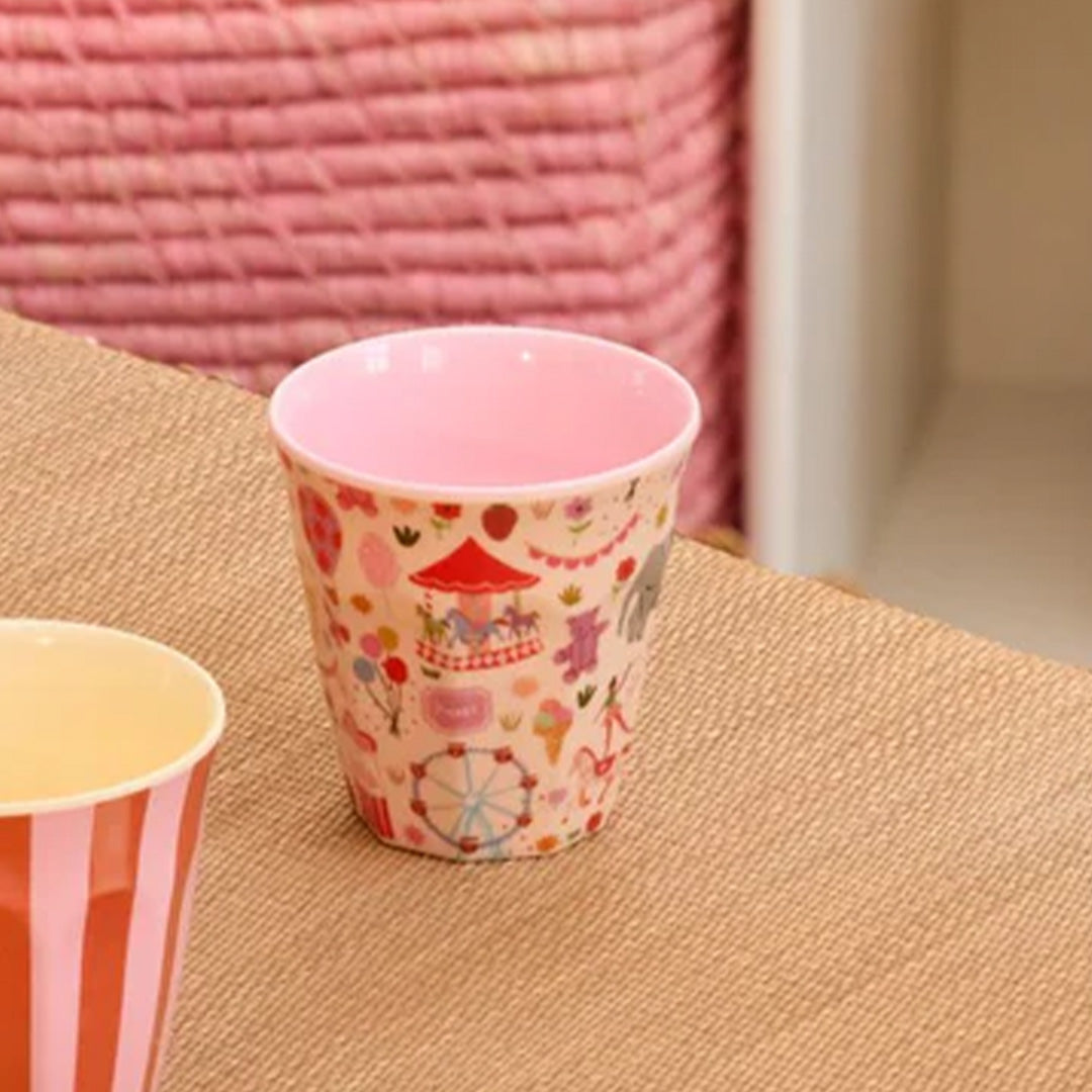 Rice kinderbeker met kermispatroon op een tafel met een roze achtergrond.