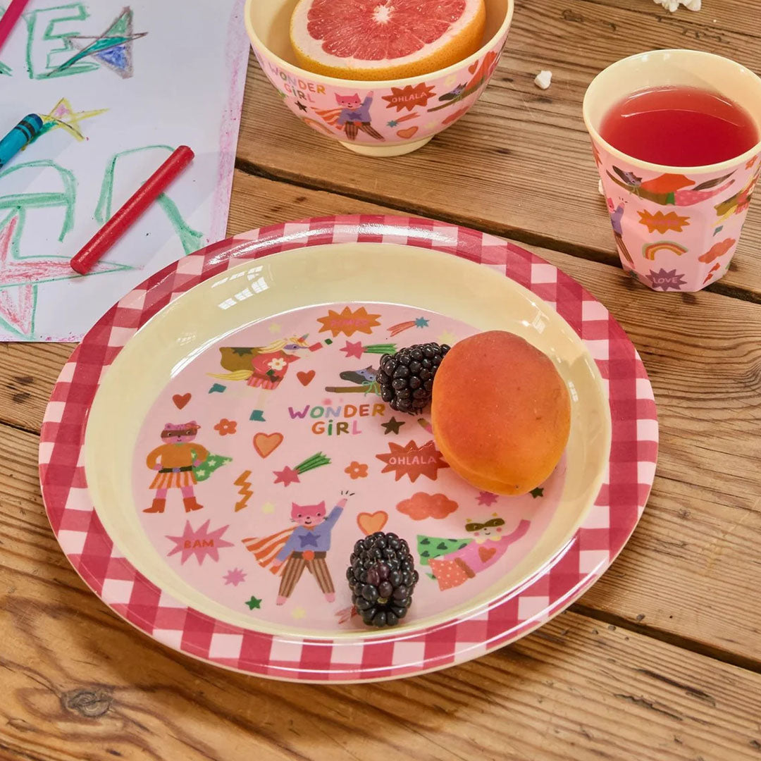 Rice kinderbord met Wonder Girl print, gevuld met fruit, op een houten tafel met bijpassende kom en beker.