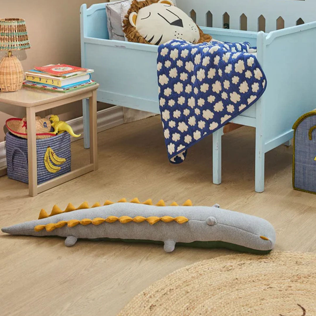rice pluchen knuffelkrokodil in een kinderkamer, liggend op een vloerkleed.