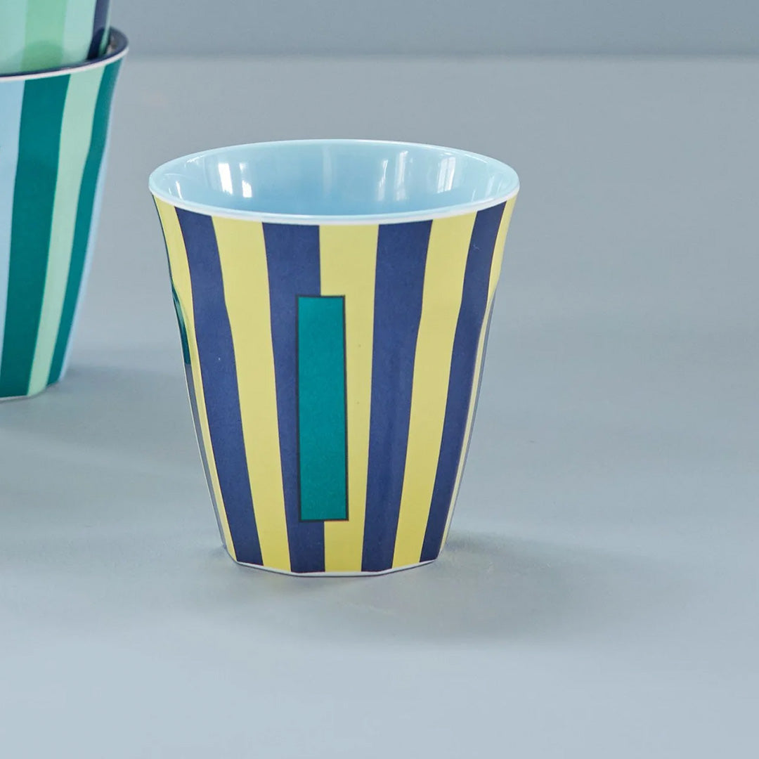 rice plastic alfabetbeker met blauw-gele strepen en de letter I op een grijze ondergrond.