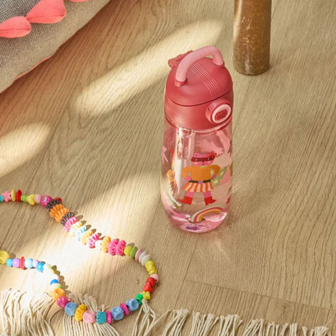 rice kinder drinkfles met superheldenfiguren op een houten vloer naast een kralenketting.