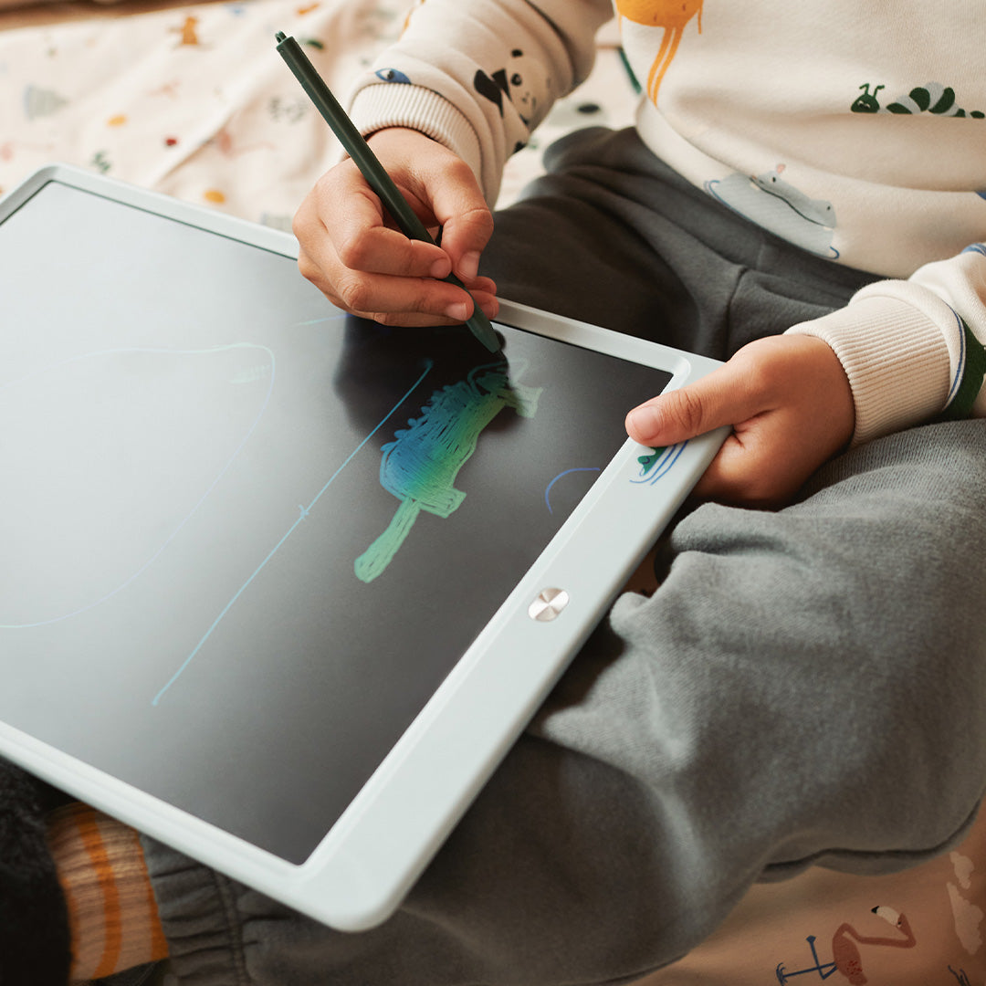Een kind tekent met een groene stylus op de duifblauwe tekentablet, waarop een kleurrijke tekening van een dier te zien is.