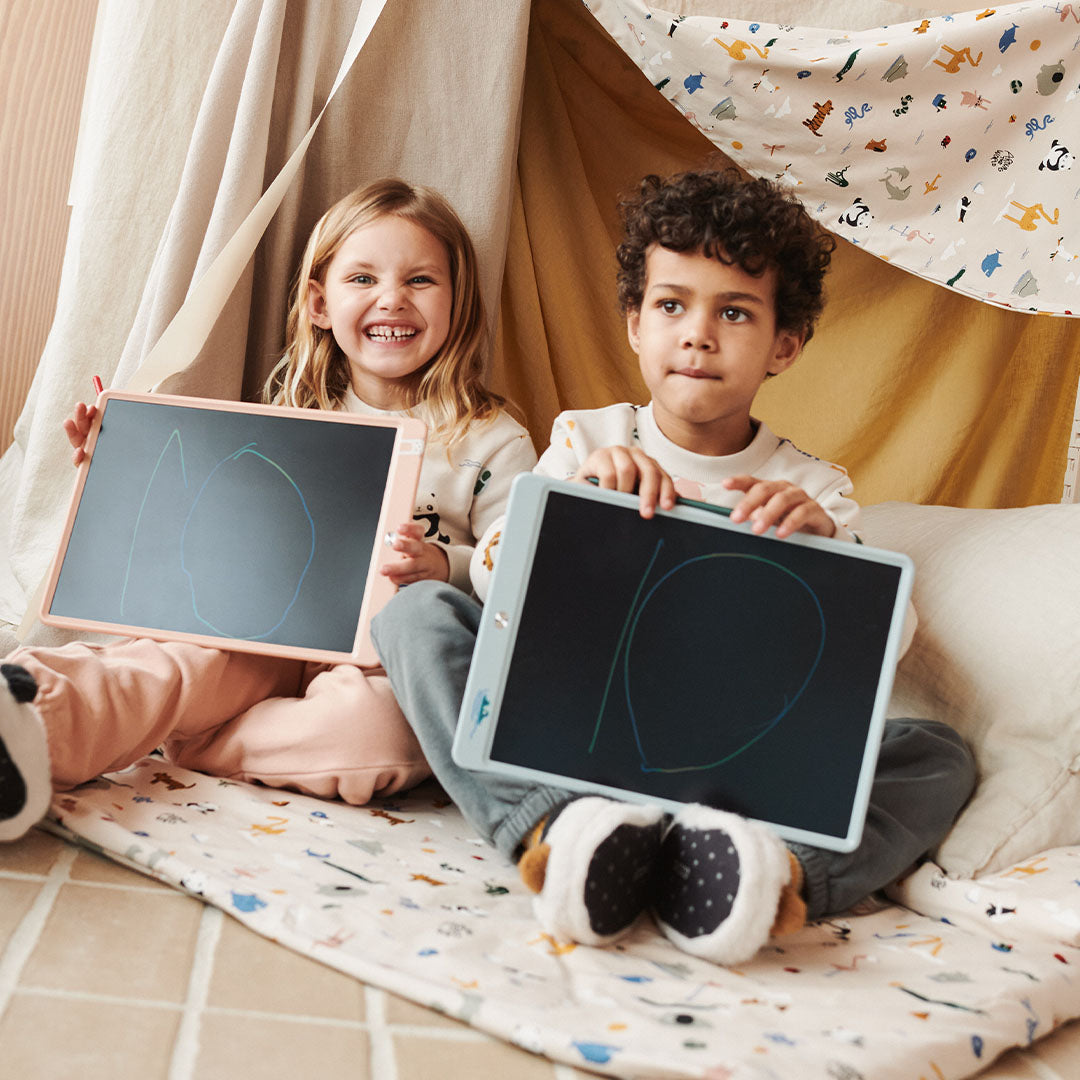 Twee lachende kinderen houden hun Liewood tekentabletten met tekeningen omhoog.