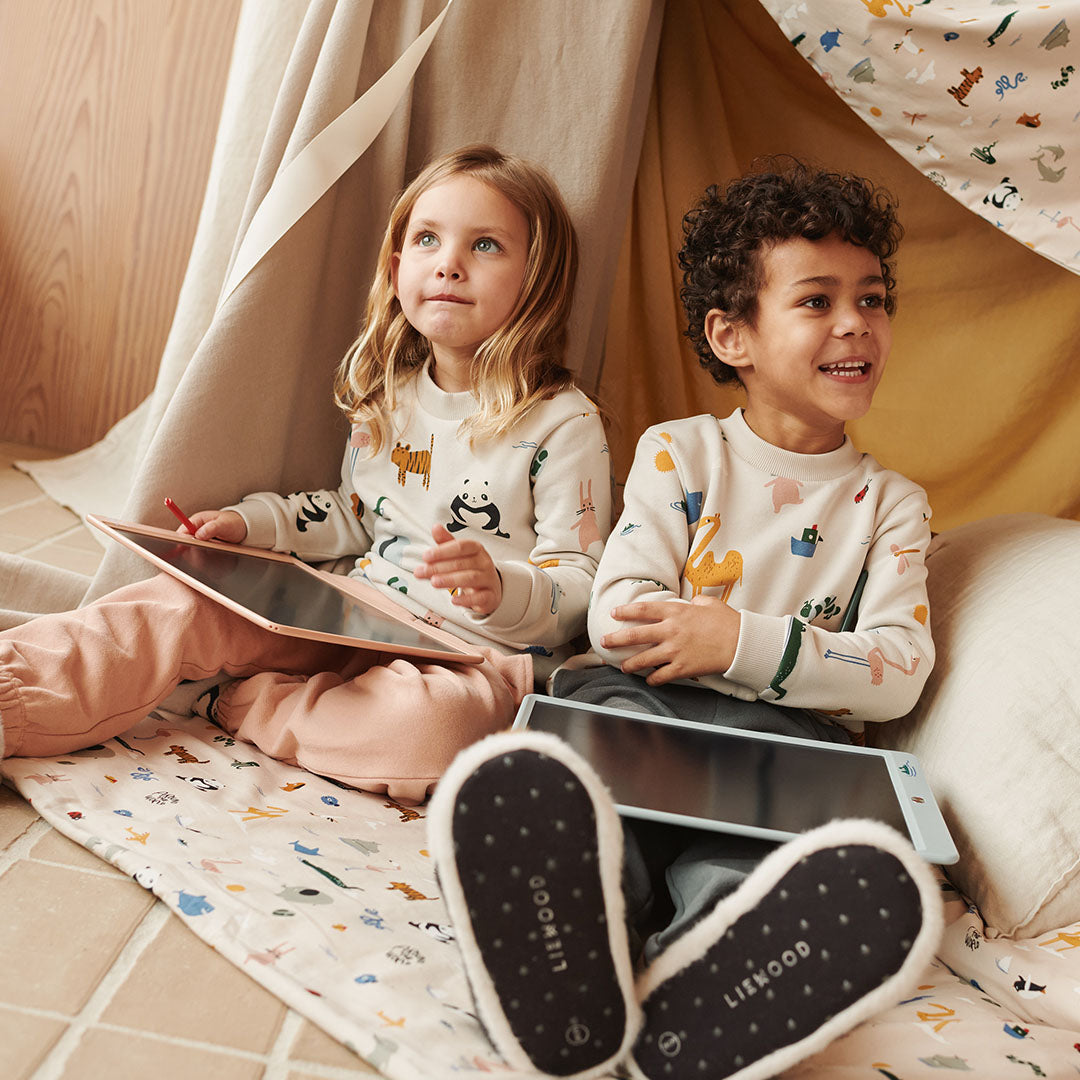Twee kinderen zitten in een speeltent met Liewood tekentabletten.