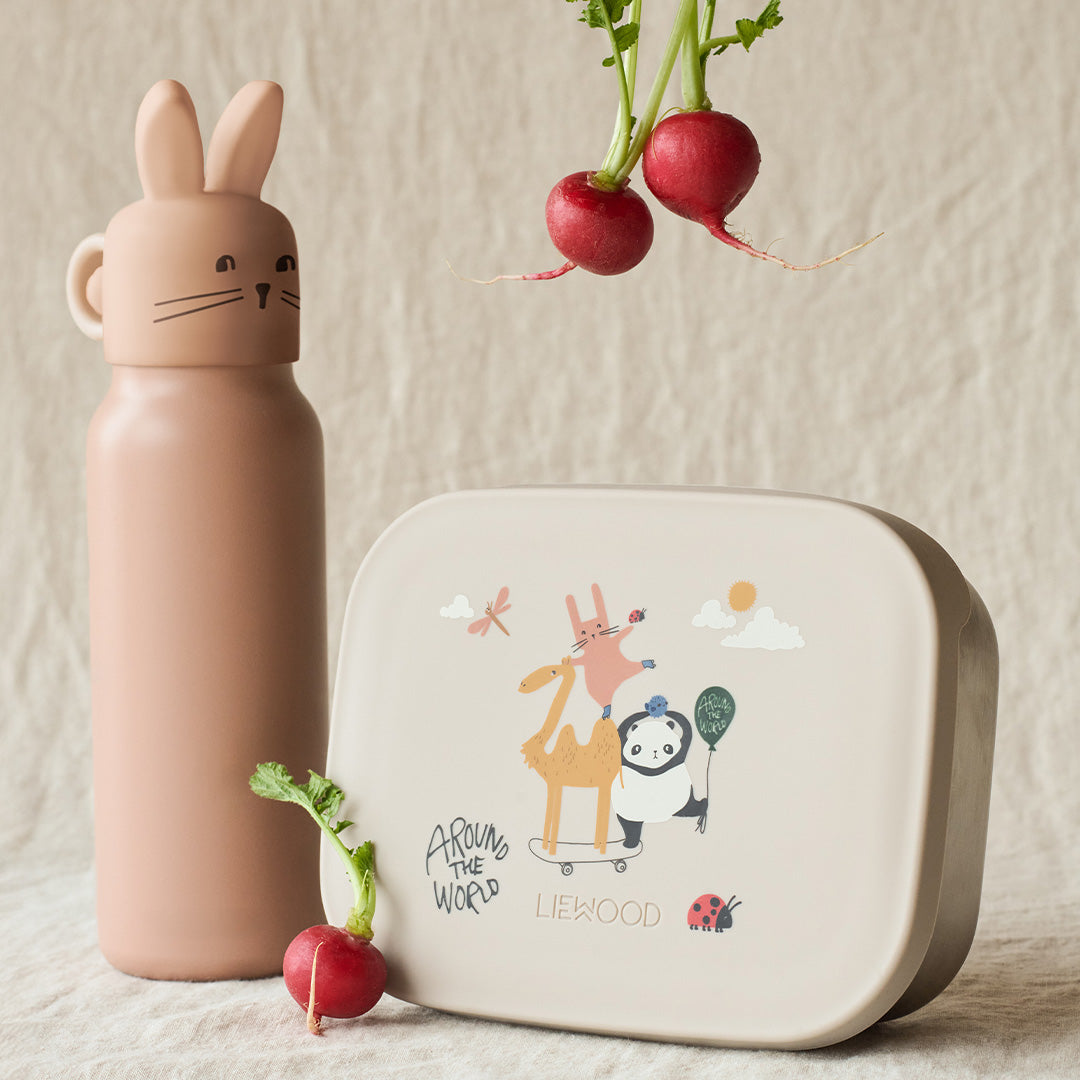 Liewood roze thermosfles met konijnenkop naast een beige lunchbox met dierenprint en radijsjes.
