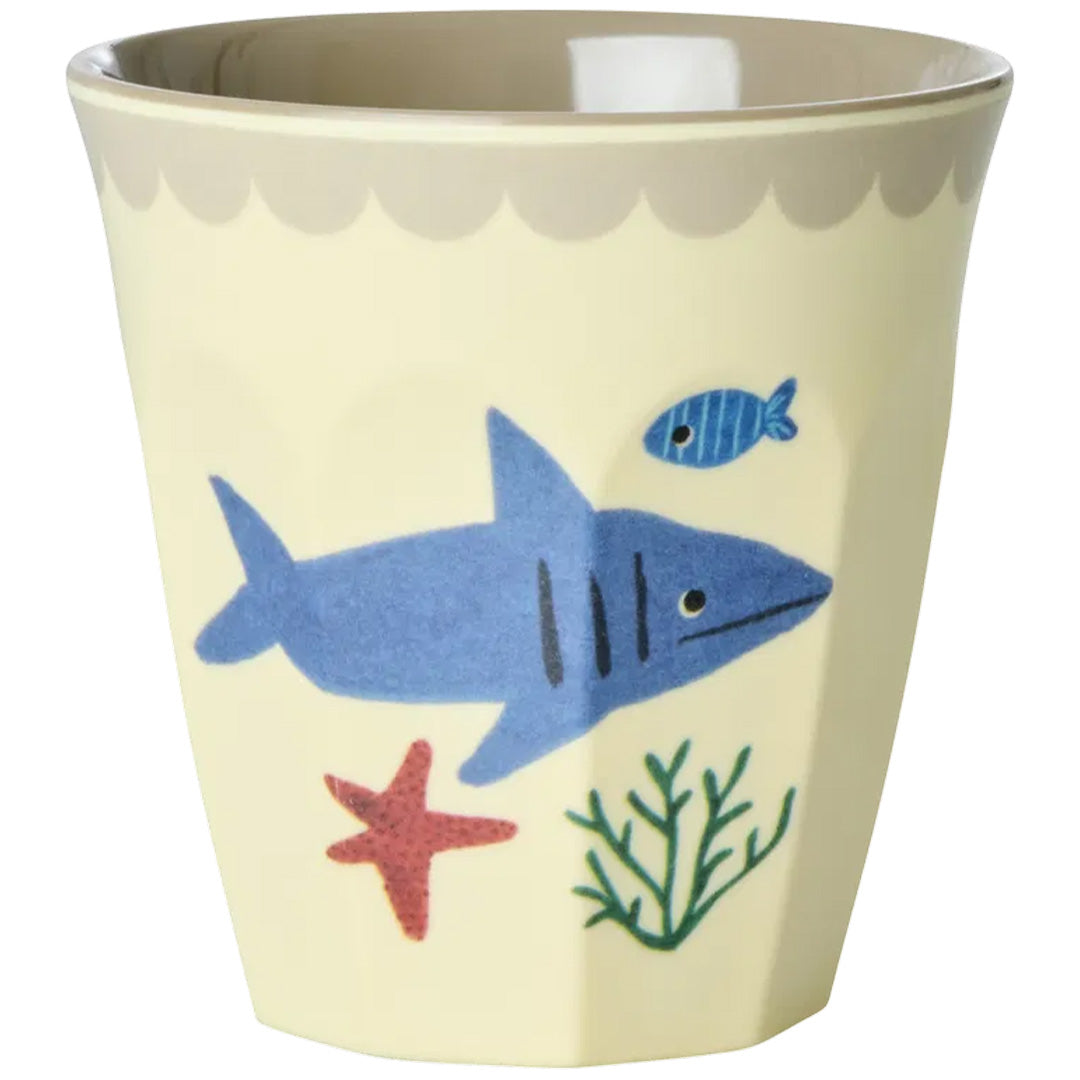 Een Rice kinderbeker met een blauwe haai, rode zeester en groene planten op een beige achtergrond.