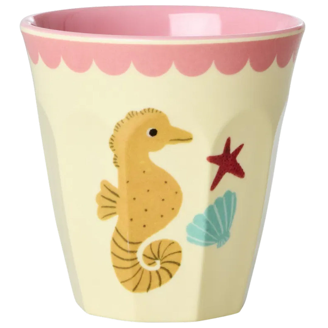 Crèmekleurige rice kinderbeker met een zeepaardje, zeester en schelp, en een roze geschulpte rand.
