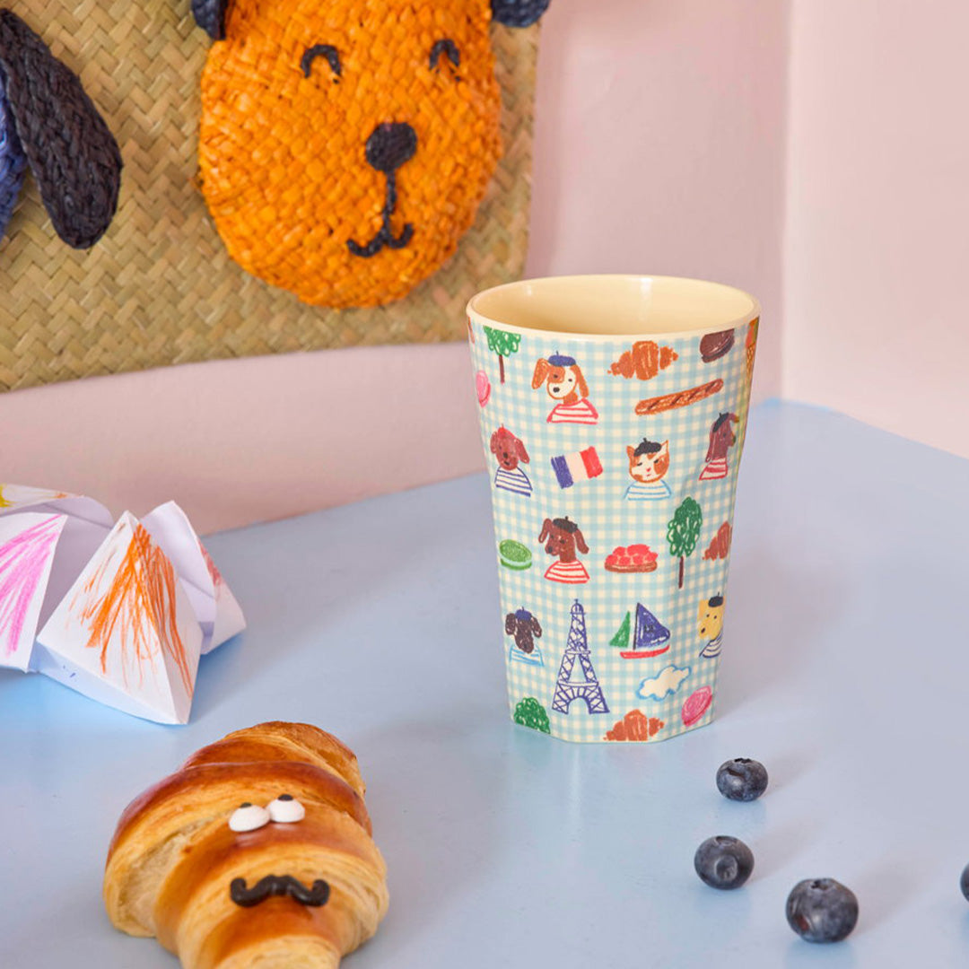 De kinderbeker met Kids in Paris patroon staat op een tafel naast een croissant en bosbessen.