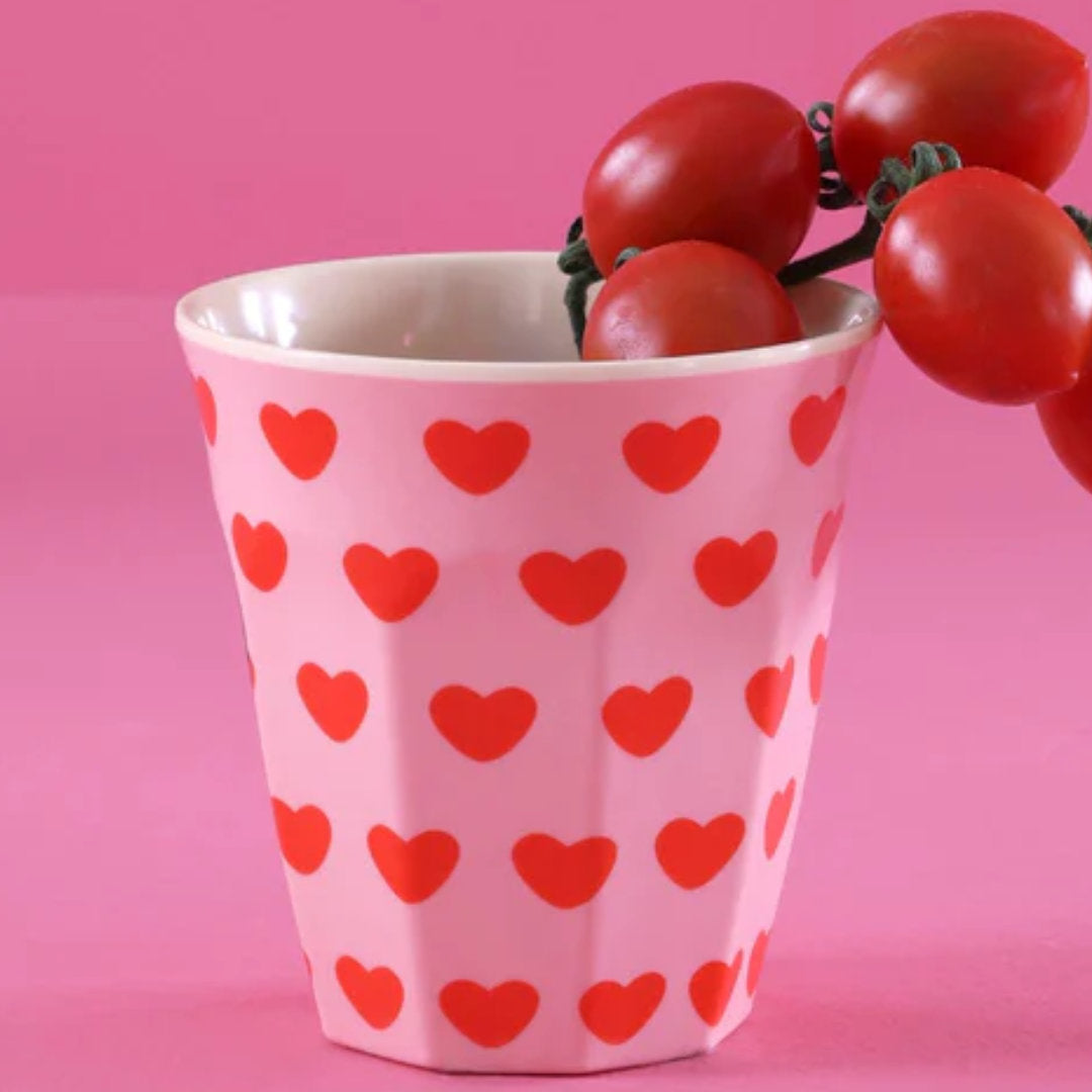rice roze kinderbeker met rode hartenpatroon, gevuld met cherrytomaten.