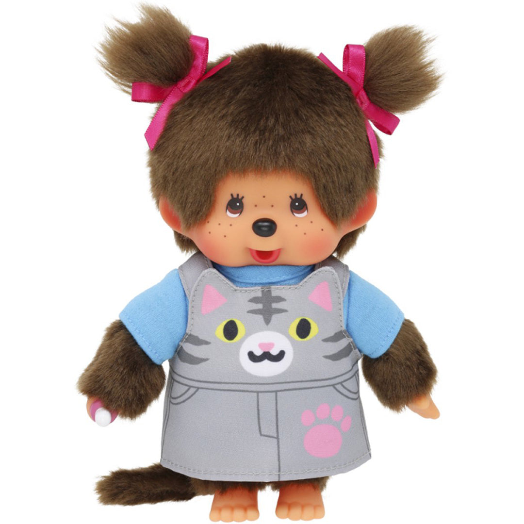 Monchhichi pop meisje met bruin haar, een blauw shirt en een grijze jurk met poes-thema, met een speen in de hand.