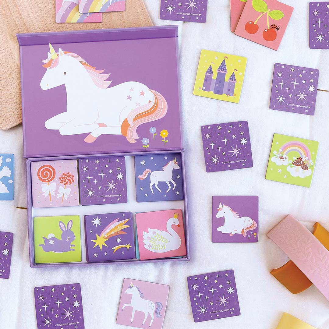 De open paarse A Little Lovely Company Unicorn Dreams memory doos met kaarten en losse kaarten verspreid op een witte ondergrond, naast houten speelgoed.
