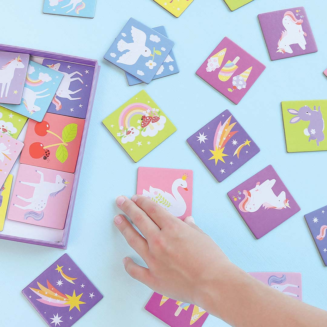 Een hand pakt een A Little Lovely Company Unicorn Dreams memory kaart met een zwaan erop, omringd door andere kaarten met diverse figuren.