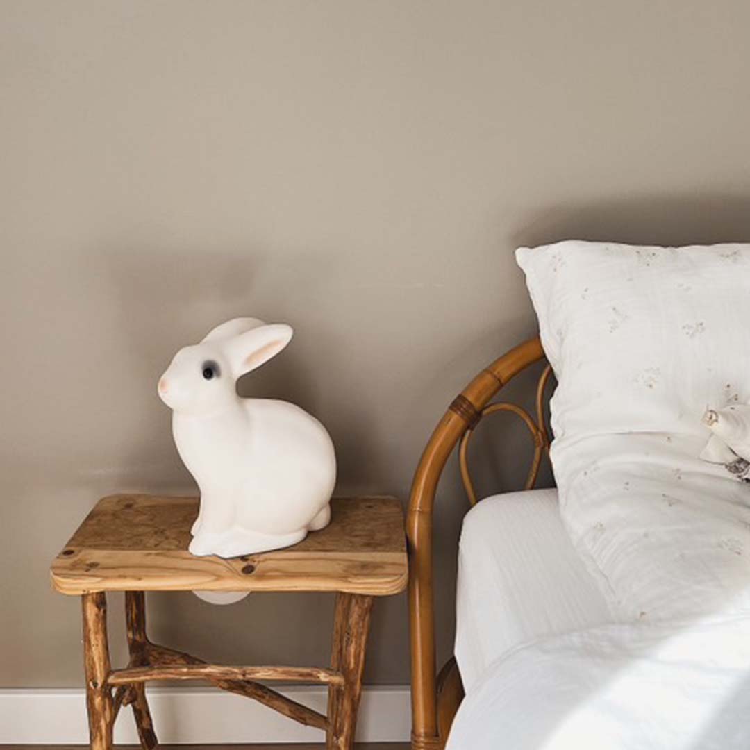 Egmont Toys konijnen nachtlamp op een houten krukje naast een bed in een kinderkamer.