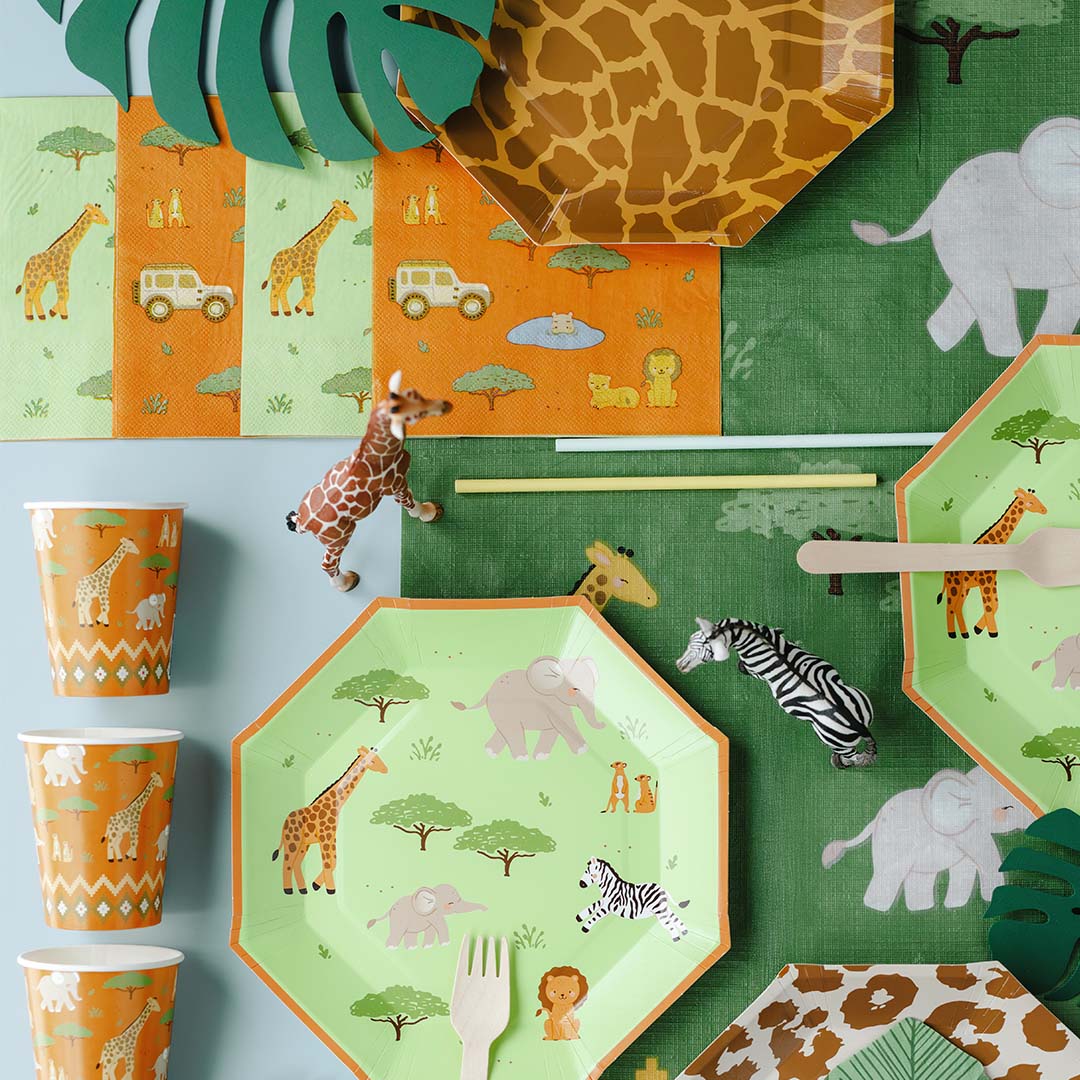 PartyDeco safari feestartikelen met servetten, borden, bekers en speelgoed dieren op een groene en blauwe ondergrond.
