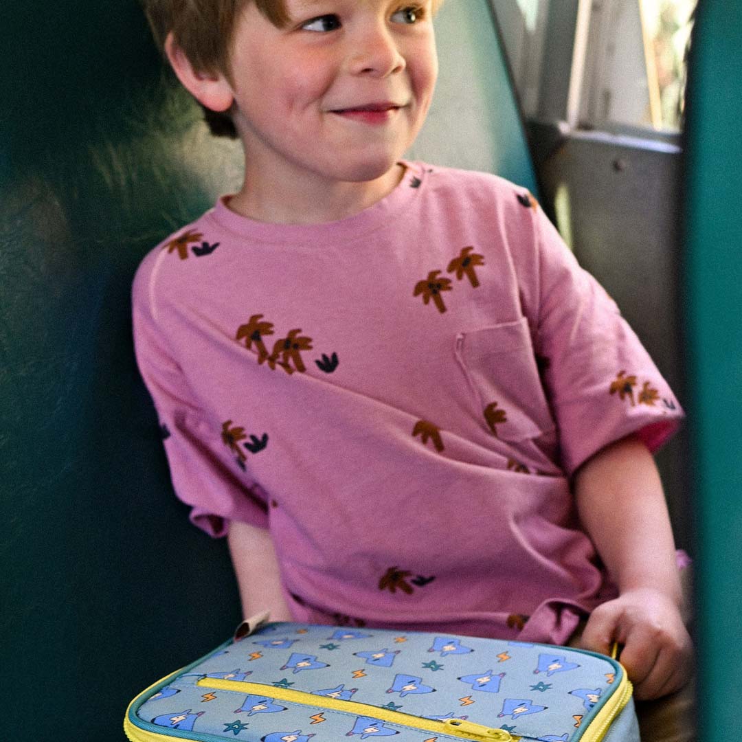Een jongen zit met de the cotton cloud koeltas met hondenpatroon voor zich.