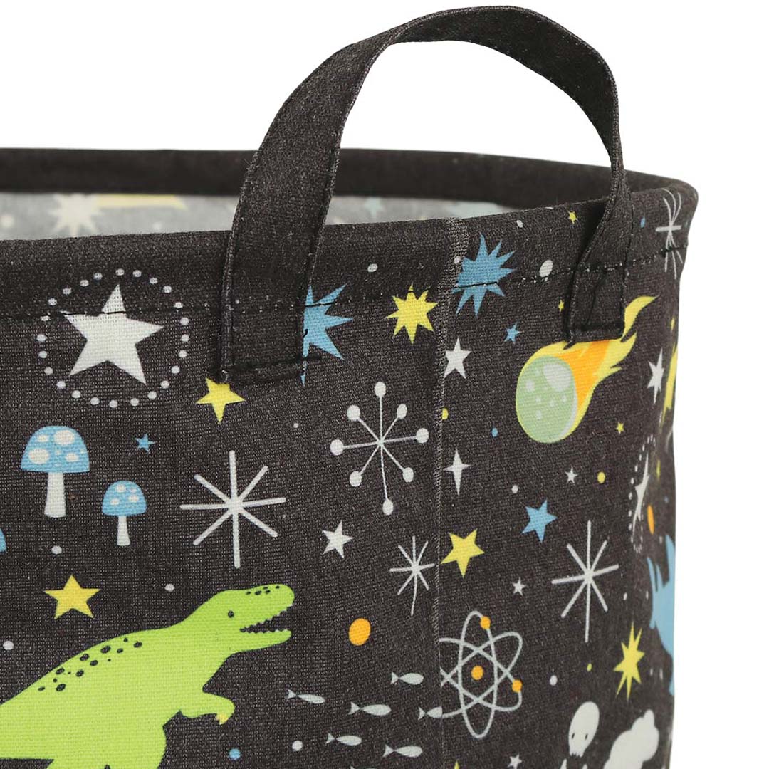 Detailopname van de A Little Lovely Company opbergmand met galaxy print, waarop een groene dinosaurus en sterren te zien zijn.