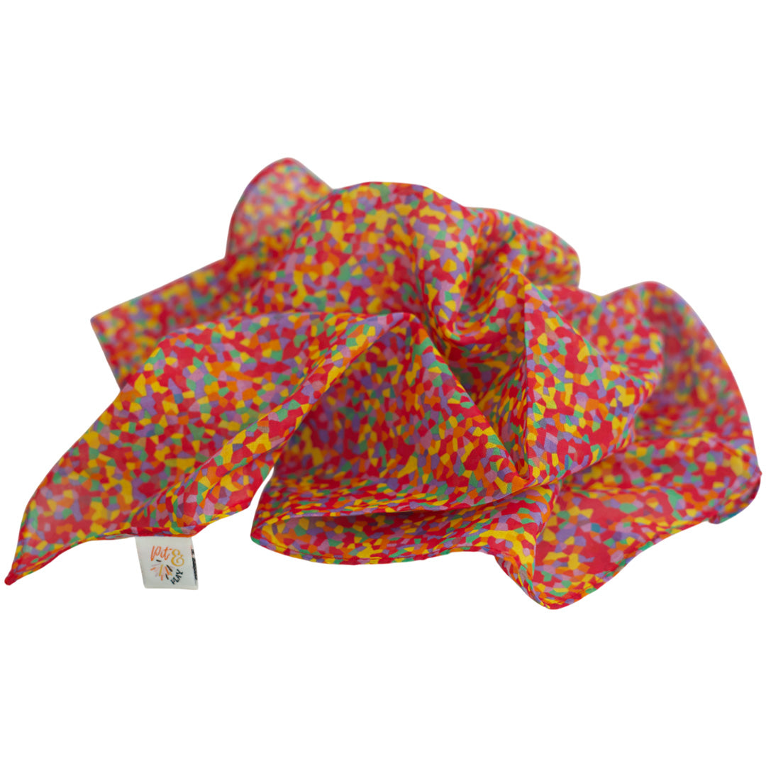 Een opgevouwen pit and play speeldoek met kleurrijk confetti patroon.