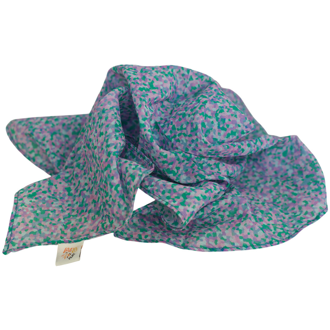 Een opgevouwen pit and play speeldoek met een paars-groen stippenpatroon.
