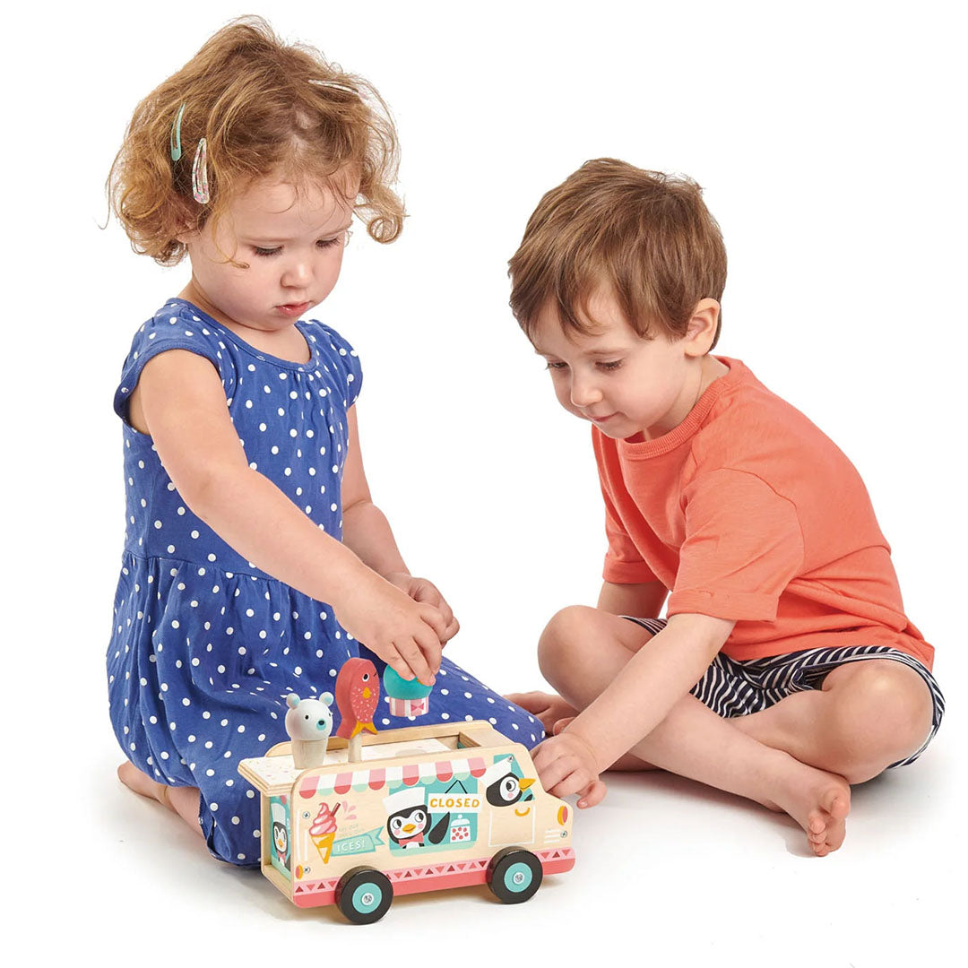 Twee kinderen spelen op de grond met de Tender Leaf Toys houten ijscowagen.