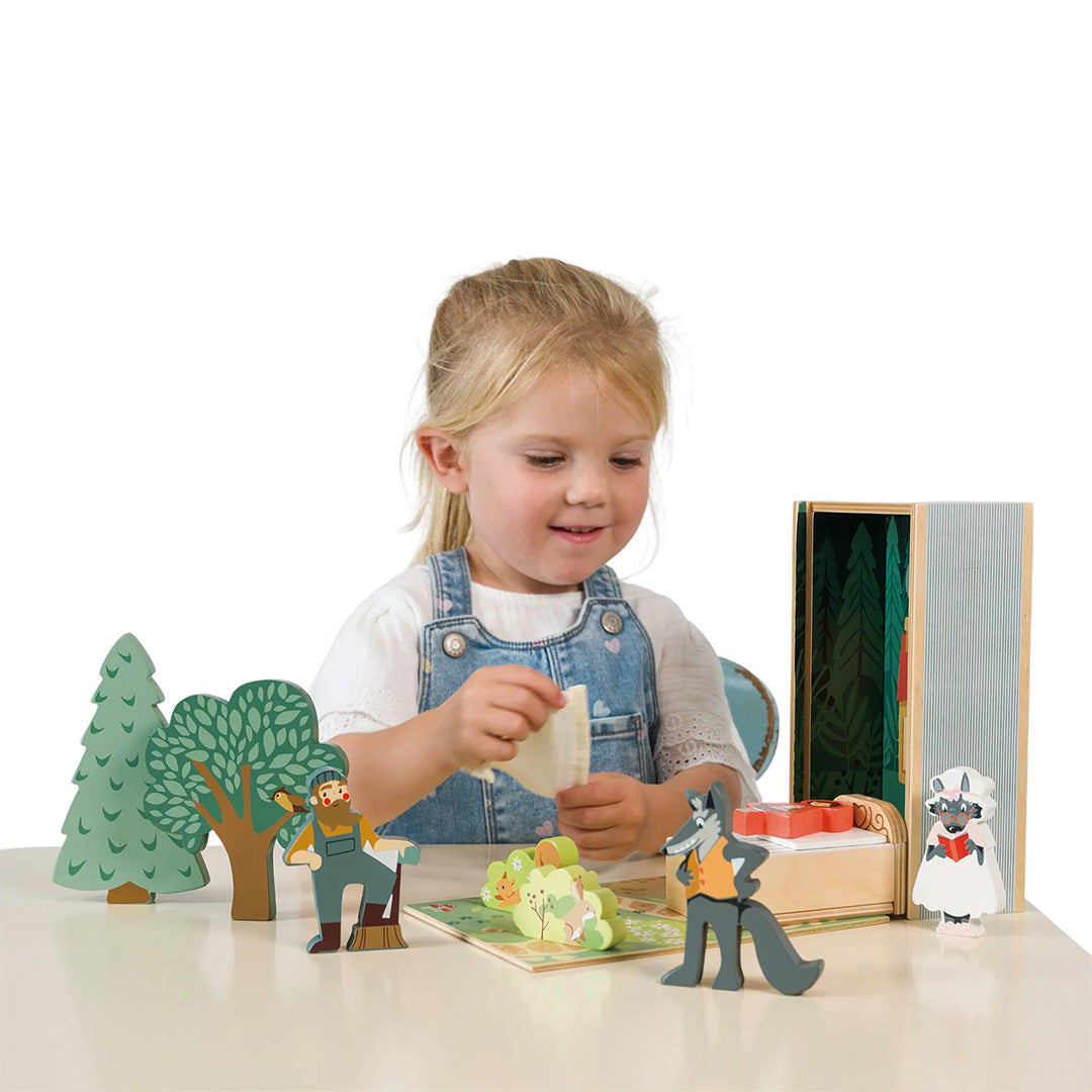 Een meisje speelt met de Roodkapje speelset, met houten figuren van de wolf, oma en de jager.