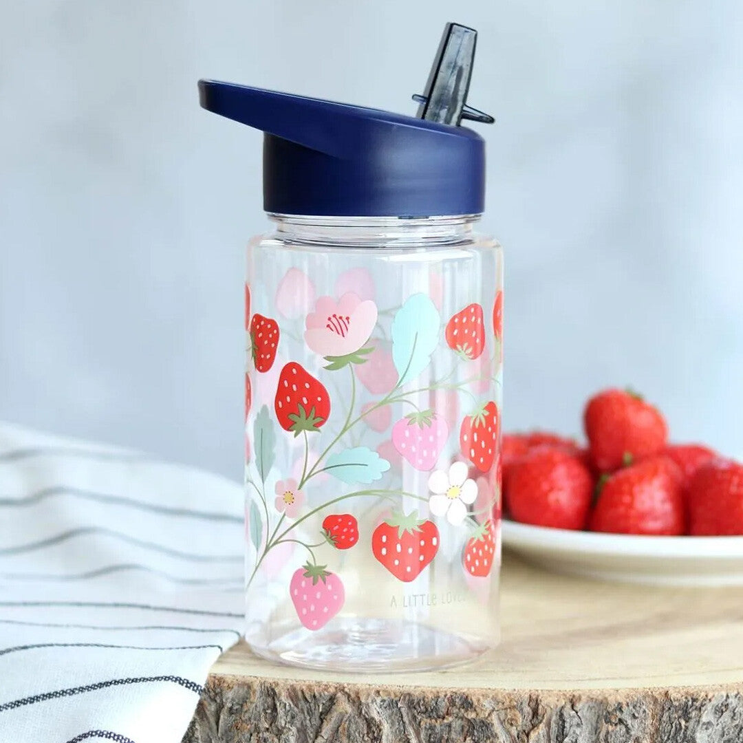 A little lovely company drinkfles met rietje voor kinderen met aardbeienpatroon, staand op een houten ondergrond met verse aardbeien op de achtergrond.
