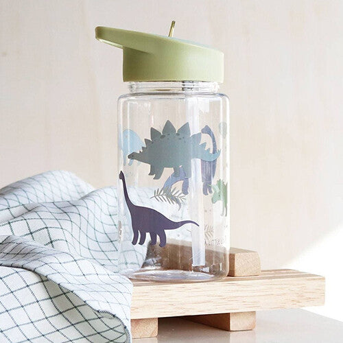 Dinosaurus drinkfles met rietje op een houten blok met een geruite doek.