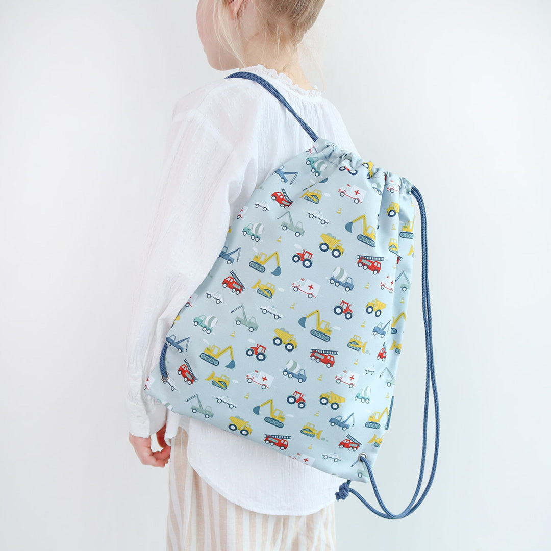 Kind draagt de a little lovely company kinder gymtas met voertuigenpatroon op de rug.