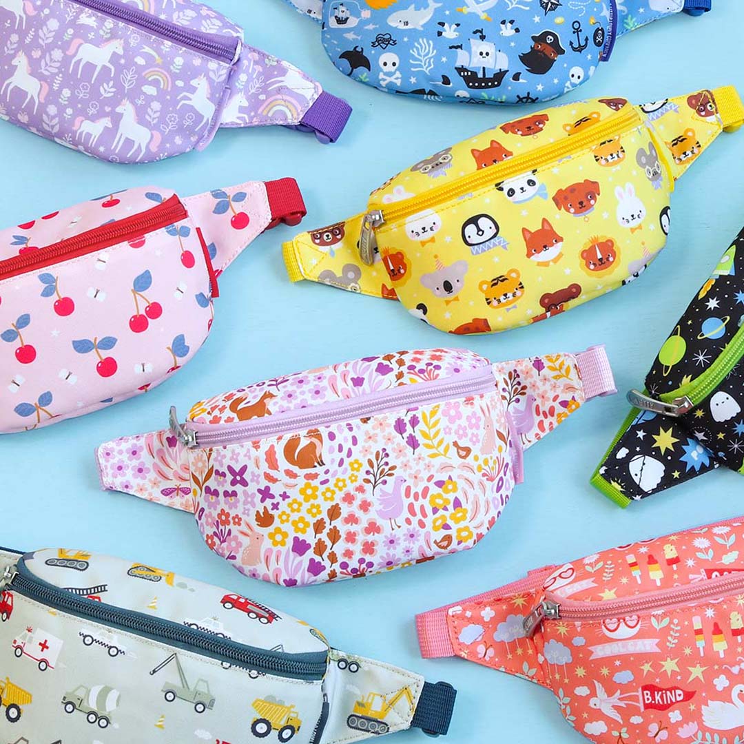 Een collectie van diverse kinderheuptassen met verschillende patronen, waaronder de gele met dierenhoofden.