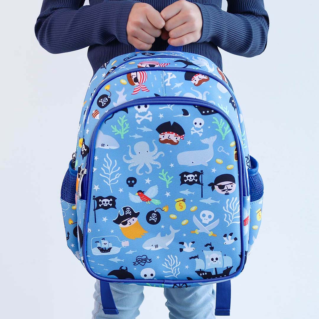 Een kind houdt de a little lovely company kinderrugzak met piratenprint vast.