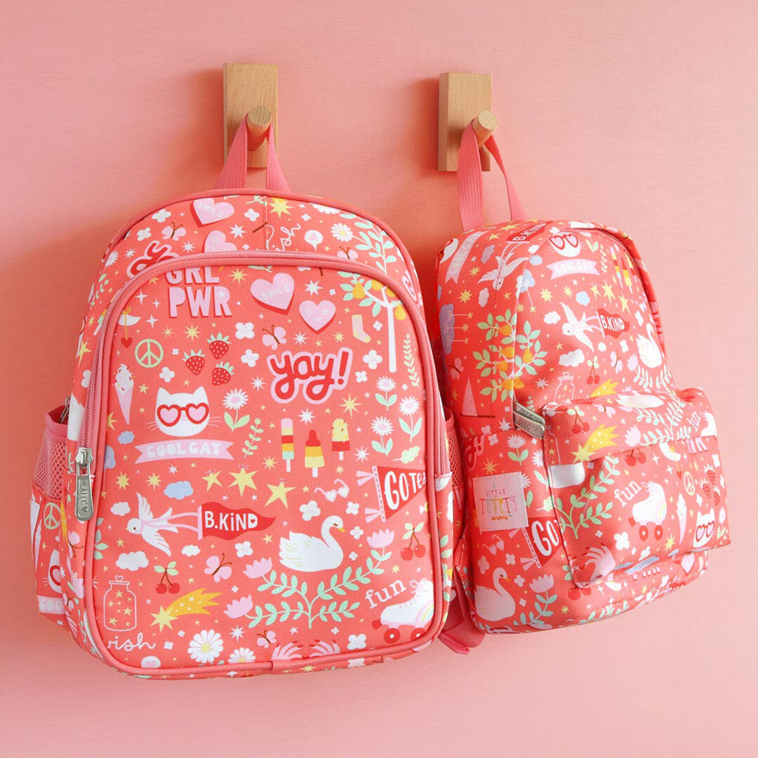 Twee roze a little lovely company kleuterrugzakken met 'fun' patroon, hangend aan houten haken tegen een roze muur.