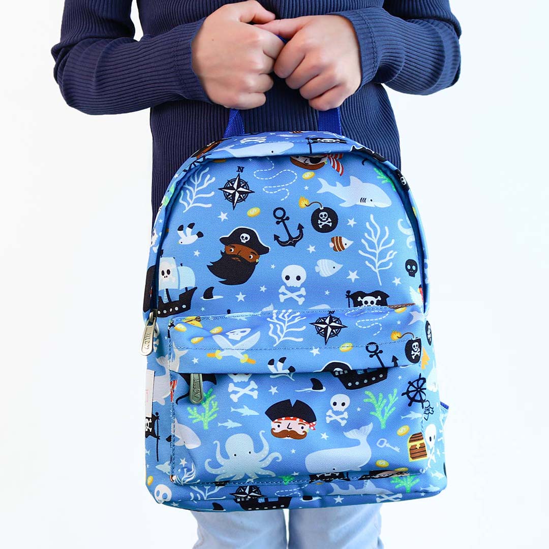 Een kind draagt de a little lovely company kleuterrugzak met piratenthema.