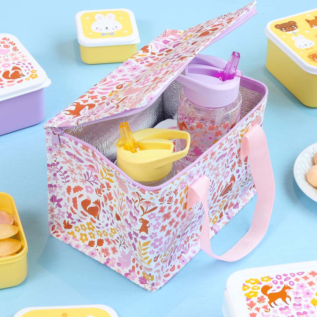 De open a little lovely company koeltas met bloemen- en dierenpatroon, gevuld met drinkflessen en omringd door lunchboxen.