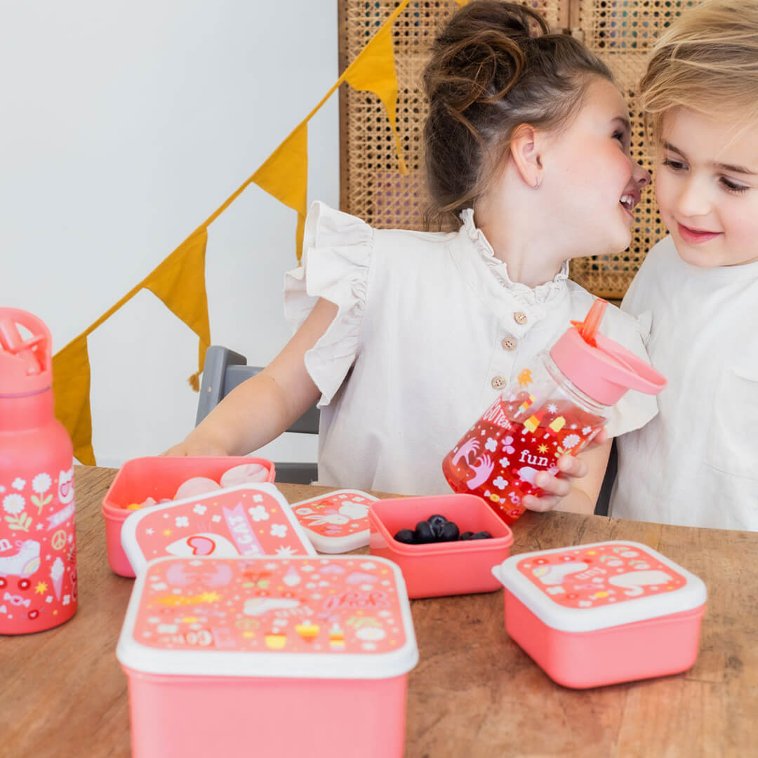 Twee kinderen aan tafel met A Little Lovely Company lunchboxen en een drinkfles.