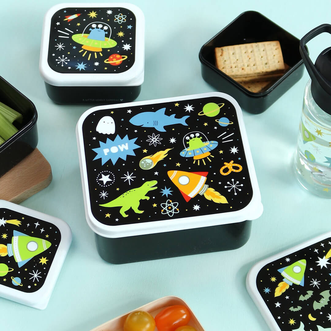 Een a little lovely company broodtrommelset met galaxy-thema, met een grote gesloten lunchbox en twee open lunchboxen met crackers en selderij.