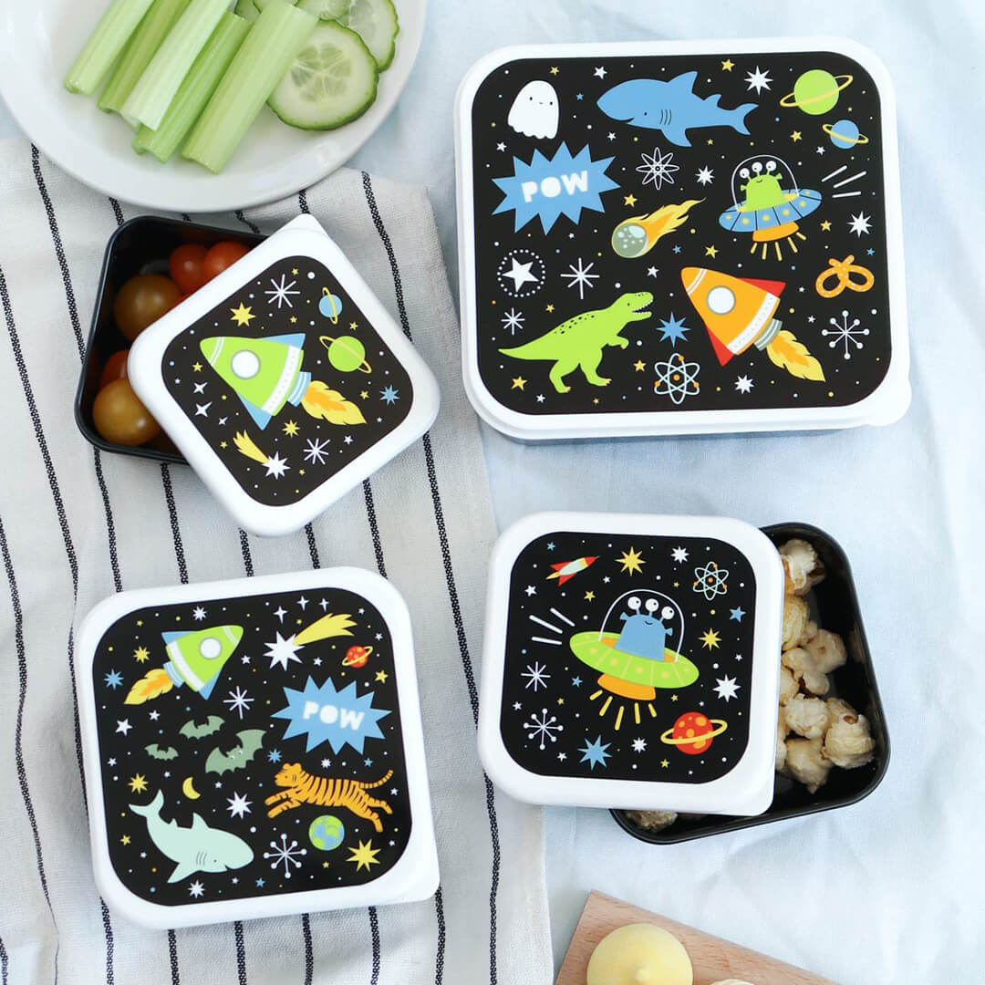 Een a little lovely company broodtrommelset met galaxy-thema, met open en gesloten lunchboxen gevuld met snacks zoals cherrytomaten en popcorn.