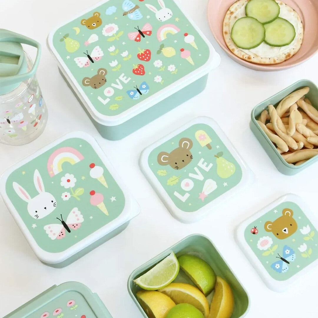 De A Little Lovely Company broodtrommelset met groene lunchboxen, versierd met dieren en regenbogen, gevuld met snacks en fruit op een witte ondergrond.