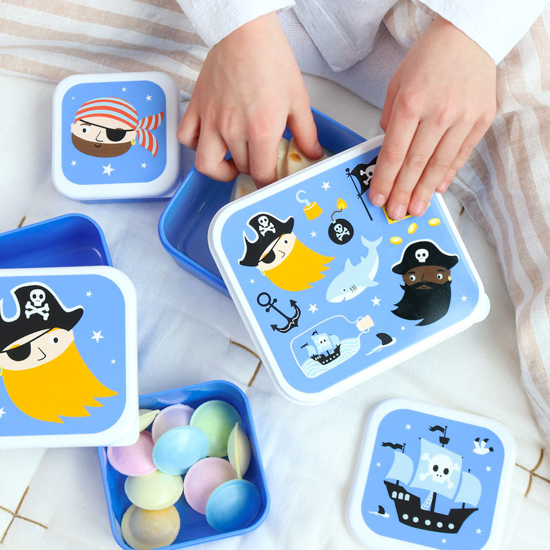Een kind opent een van de A Little Lovely Company kinderbroodtrommels in piratenthema, met snoepjes in een andere box.
