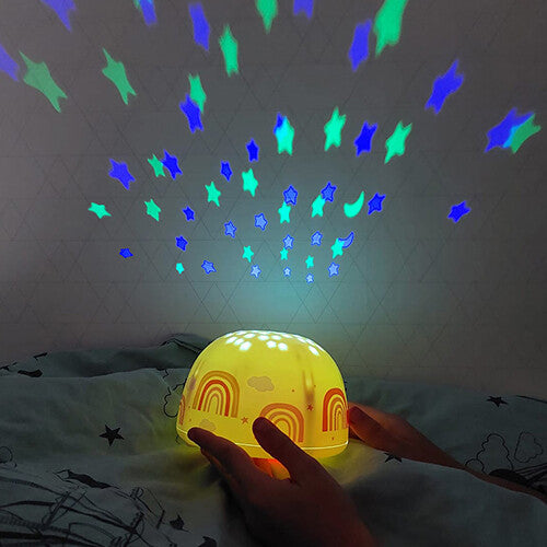 Een a little lovely company nachtlamp en sterprojector projecteert blauwe en groene sterren op een muur, vastgehouden door handen.